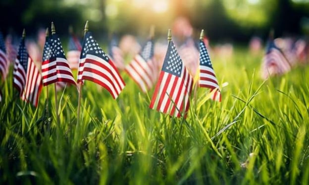 Hundreds of American Flags stuck into the grass at golden hour in honor of Memorial Day.