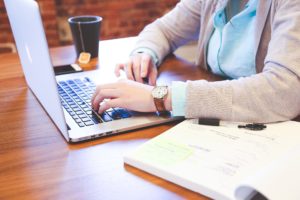 Senior associate sitting at his laptop, with a cup of tea, reaching out to his audience via social media
