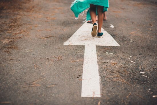 Woman walking on an empty road with her child in front of her