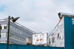 Urban setting a billboard with 2 animated figures about to kiss, with a caption that reads, Stay Human