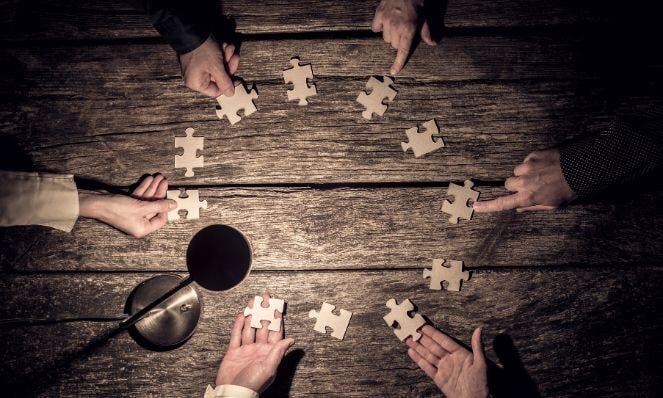 People holding puzzle pieces with a spotlight overhead.
