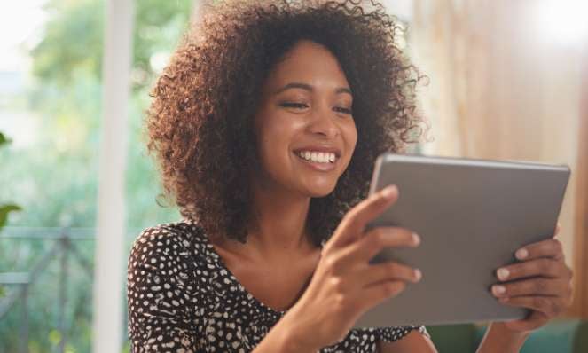 Woman smiling holding and looking at tablet